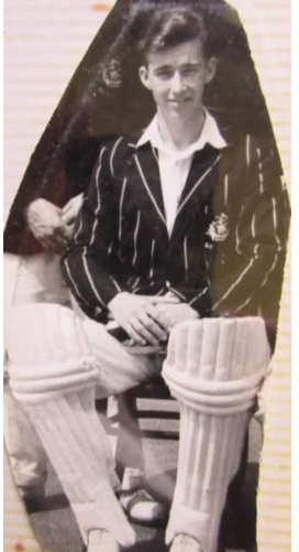 A young cricketer in pads and blazer